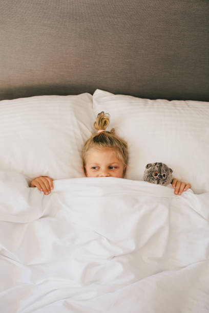istock Cute little girl having fun lying in bed. 1477460388