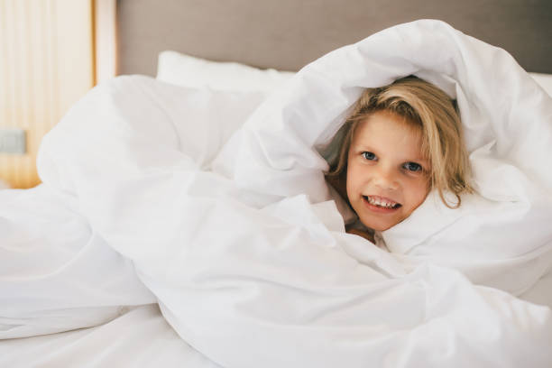 istock Cute little girl having fun lying in bed. 1477460402