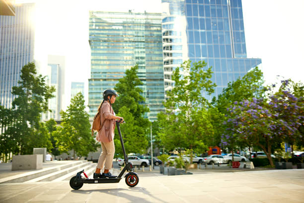 Late 30s businesswoman riding electric push scooter stock photo