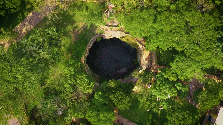 Aerial view of cenote Saamal in Valladolid, Mexico. People rest and swim in cenote. 
A small waterfall in a cenote.