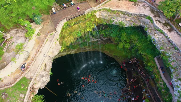 Aerial view of cenote Saamal in Valladolid, Mexico. People rest and swim in cenote. 
A small waterfall in a cenote.