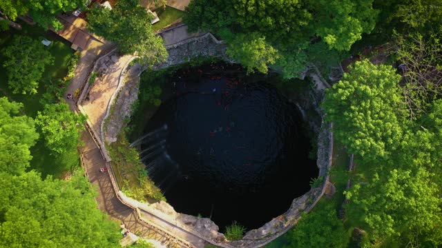 Aerial view of cenote Saamal in Valladolid, Mexico. People rest and swim in cenote. 
A small waterfall in a cenote.