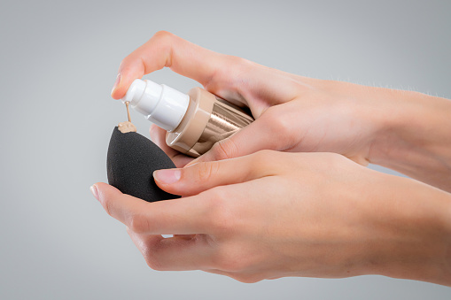 Hand with makeup sponges on white background