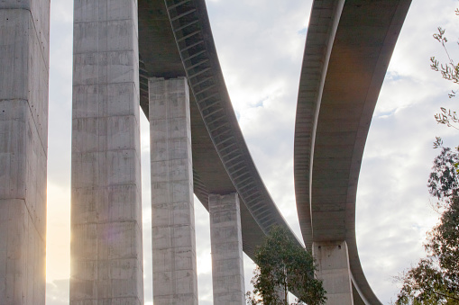 Two large concrete highway viaducts from below. Gold colored sunbeam. Asturias, Spain.