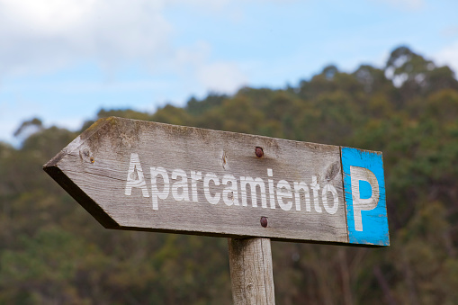 Parking sign wooden post in a hiking route, forest background, craft hiking pole, parking sign . Asturias, Spain.