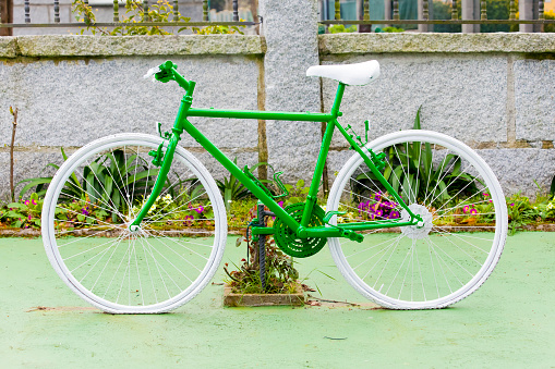 Old bicycle painted green leaning in the street, decoration purposes, Asturias, Spain.