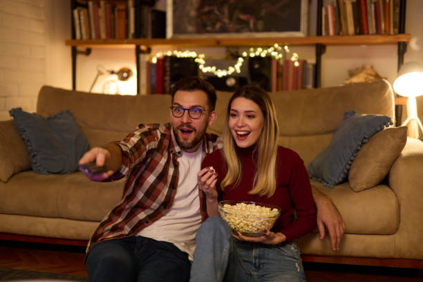 istock Young romantic couple watching TV at home 1477471269