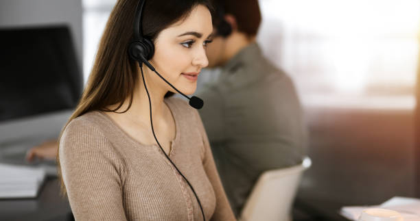 istock Call center operators at work. Two young people in headsets are talking to the clients, while sitting in sunny office 1477471639