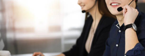 istock Young man with headsets is talking to a client, while sitting in modern sunny office. Call center operators at work 1477471652