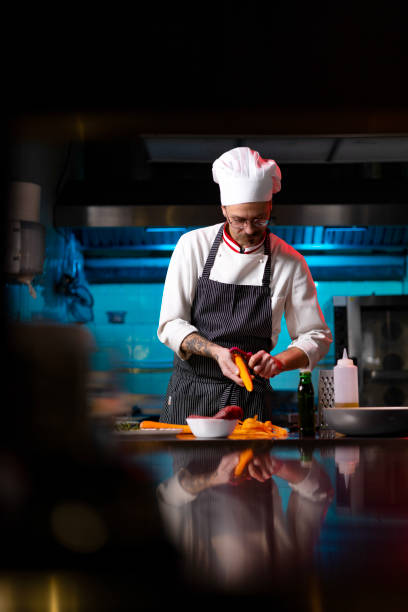 istock Professional chef peeling fresh carrot in commercial kitchen. 1477474824