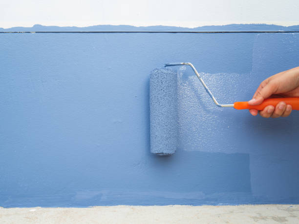 istock Bare hand holding the handle of the paint roller. pastel blue dip Rolled paint over the old wall. to repair old deteriorated walls Renovation and home decoration 1477475509