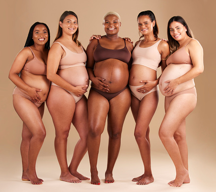 Pregnancy, diversity and portrait of friends in studio for community, motherhood and prenatal wellness. Maternity, love and pregnant women showing their baby bump stomach together by beige background
