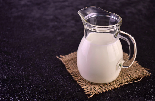 Carafe of milk on a light blue background. Close-up.