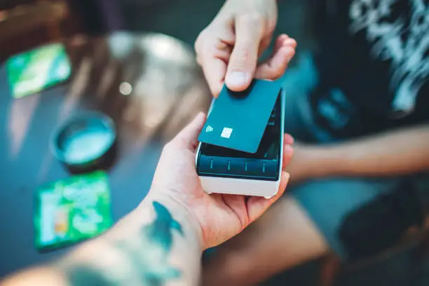 Photo of Adult man paying with credit card at cafe, close-up of hands with credit card and credit card reader