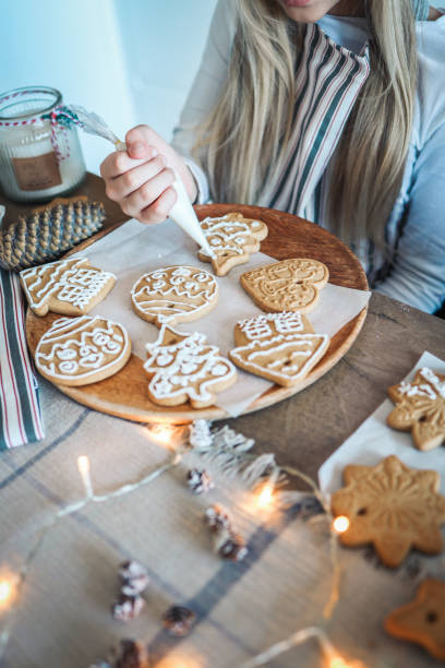 istock Christmas, New Year, holidays preparation and creativity concept. Getting ready to celebration. Woman hands decorating homemade gingerbread cookies with icing 1477483702