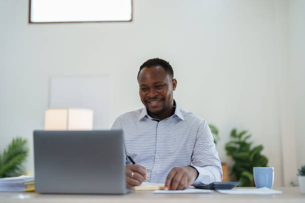 istock middle aged man American African using computer laptop with planning working on financial document, tax, exchange, accounting and Financial advisor 1477485470