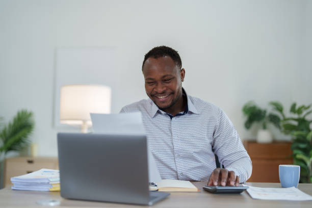 istock middle age man American African using calculator for calculating and laptop computer with planning working on financial document, tax, exchange, accounting and Financial advisor 1477485705