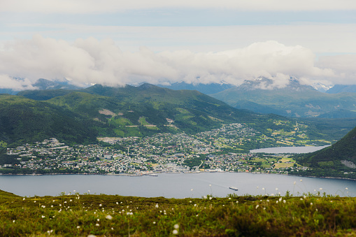 Scenic view of a Volga city by the bay of water surrounded by the green mountain peaks from top in Møre og Romsdal, Western Norway