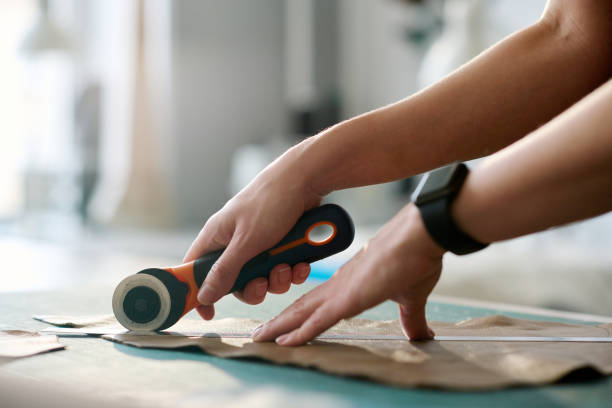 istock Hands of young female tanner with sharp knife cutting leather 1477487553