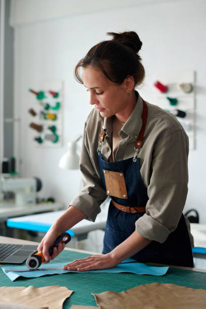 istock Young female artisan in workwear bending over table during work 1477487598
