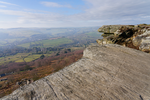 Cold, misty winter morning standing high above Hope Vally on the gritstone boulders of Curbar Edge.