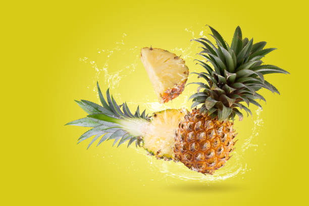 istock Water Splashing on Split Pineapple Fruit isolated on a yellow background. 1477487991