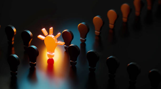 istock Yellow Light Bulb Glowing Amid Black Light Bulbs On Black Background 1477488295