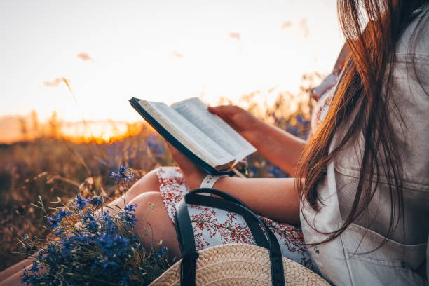 chrześcijanka trzyma biblię w rękach. czytanie pisma świętego na polu podczas pięknego zachodu słońca. koncepcja wiary, duchowości i religii. pokój, nadzieja - book reading dress women zdjęcia i obrazy z banku zdjęć