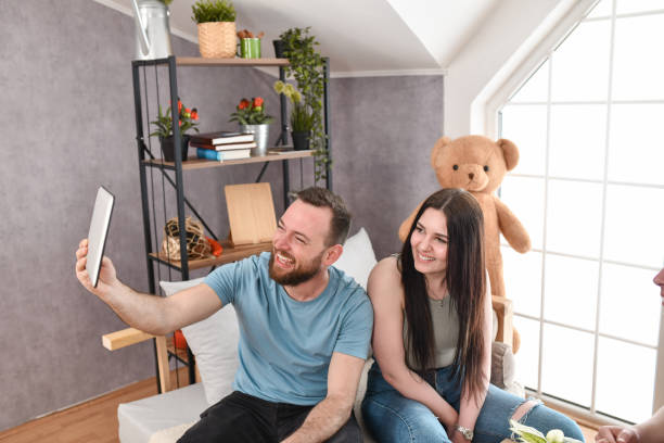 istock Cute Couple Smiling During Digital Tablet Video Conference At Home 1477488729
