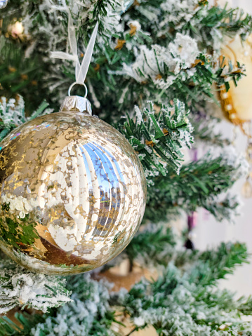 Gold glass Christmas ornament on an artificial Christmas tree.