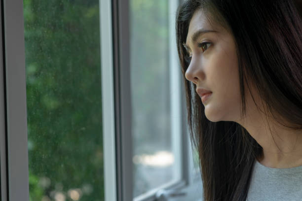istock Sad woman near window thinking about something 1477491852