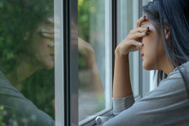 istock Sad woman near window thinking about something 1477492048