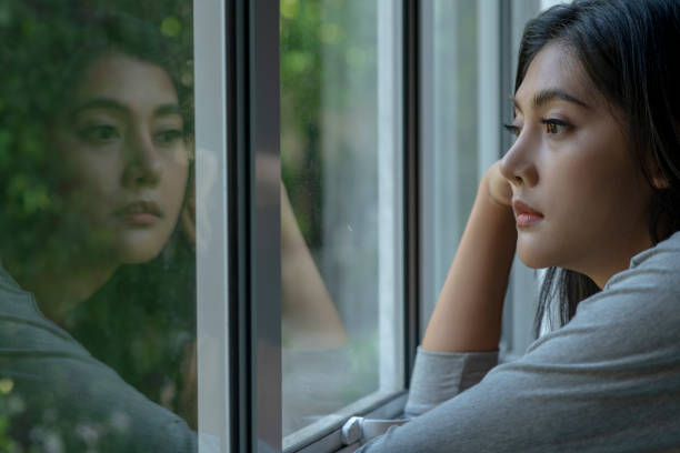istock Sad woman near window thinking about something 1477492104
