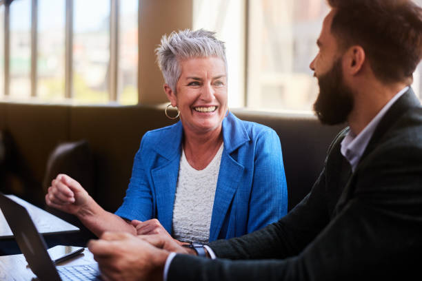 istock Two smiling businesspeople talking together over a laptop in an office 1477492448