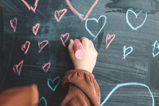 The child draws hearts on the board.