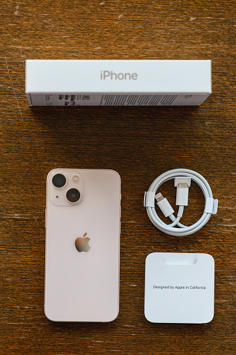 Studio shot of an iPhone 13 mini Pink, Rear view unboxing with charging cable