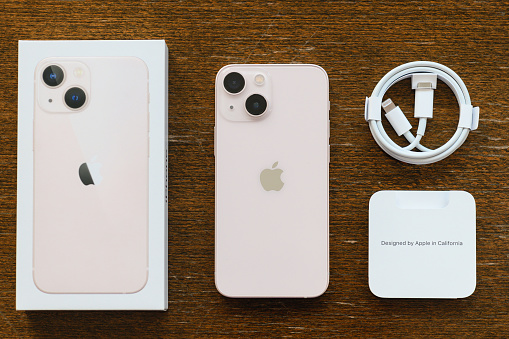 Studio shot of an iPhone 13 mini Pink, Rear view unboxing with charging cable