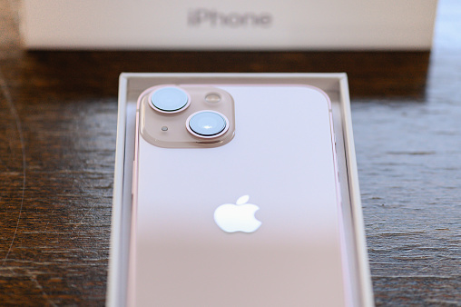 Studio shot of an iPhone 13 mini pink, from above on a wooden table. Focus on a camera