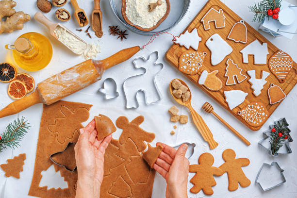 istock Christmas gingerbread different shaped with ingredients for gingerbread and the hands of a woman baker, top view, flat lay 1477494954