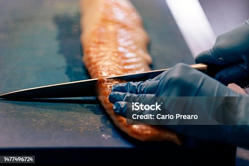 istock close up on hands in blue latex gloves cutting fish with professional knife 1477496724