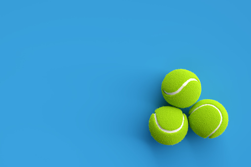 Three tennis balls on blue background with copy space. 3D rendering. Flat lay overhead view.