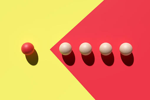 Leadership and guidance concept. Wooden spheres moving towards the red sphere. 3d rendering.