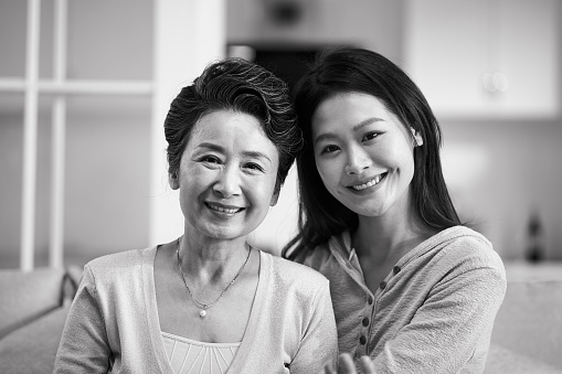 portrait of asian senior mother and adult daughter looking at camra smiling, black and white
