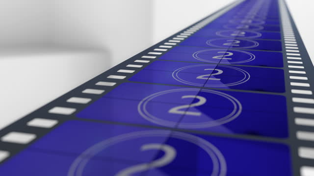Blue film strip with countdown frames moving to the cinema camera on the white