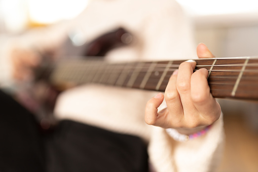 Young girl playing electric guitar at home