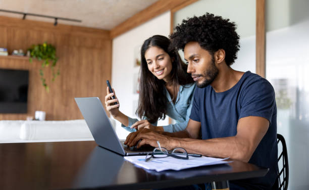 istock Couple at home paying bills online using a laptop 1477508015
