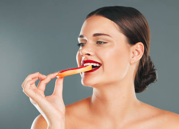 istock Fruit, smile and woman with a grapefruit for nature and wellness aesthetic in a studio. Model health eating, beauty and natural skincare of person with red lipstick hungry for vitamin c nutrition 1477509305
