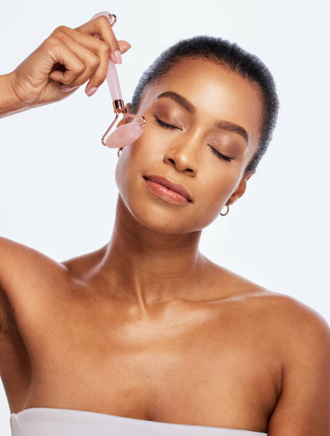 Skin care, facial roller and massage for a woman in studio for dermatology, cosmetic and natural face. Aesthetic model person with spa jade stone tools for healthy glow isolated on a white background cuidado de la piel, rodillo facial y masaje para una mujer en estudio para dermatología, cosmética y rostro natural. modelo estético de persona con herramientas de piedra de jade spa para un brillo saludable aislado sobre un fondo blanco