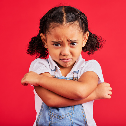 Child, arms crossed or sad portrait on isolated red background for depression, mental health or crying face. Upset, unhappy or little girl with sulking, grumpy or facial expression in bullying crisis