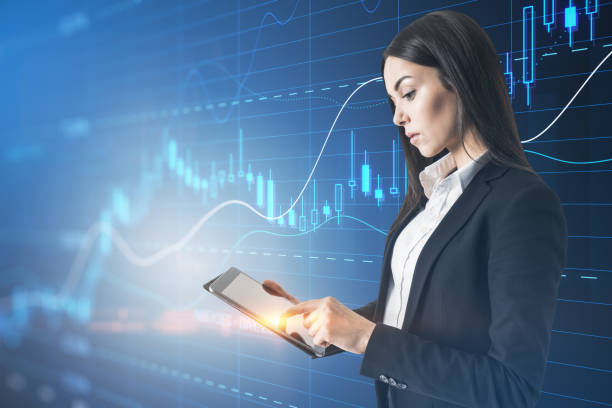 istock Attractive young european businesswoman using tablet with glowing candlestick forex chart with index on blurry blue background. Trade, stock and finance concept. Double exposure. 1477512357